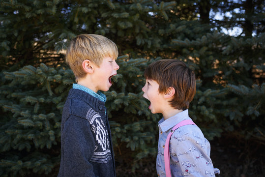 Two boys standing opposite each other with their mouths open shouting