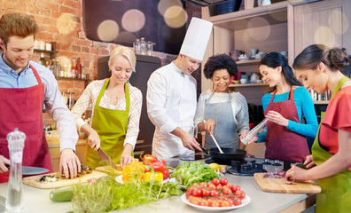 happy friends and chef cook cooking in kitchen