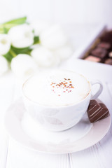 Happy Valentine's day! Coffee cappuccino with ceylon cinnamon, chocolate heart and white tulips on a white background