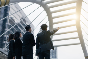 Group of business peoples standing outdoors with office building in the background, point to target