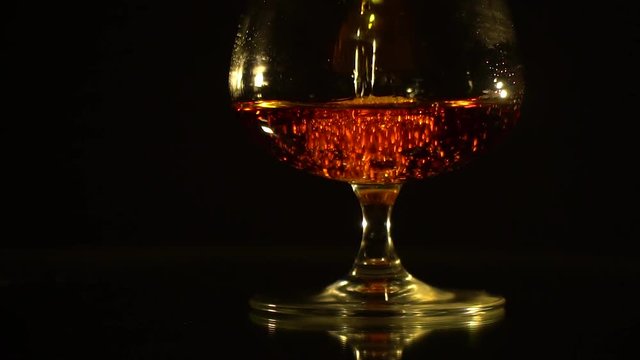 Bubbles in a glass with cognac on a black background