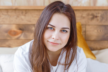 Morning bright lifestyle portrait of young pretty woman relaxing and having fun alone on bed