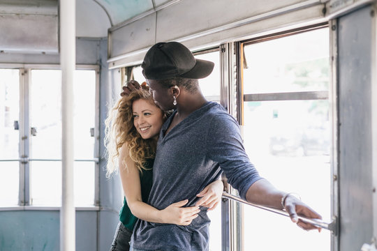 Multi ethnic young couple in love traveling on a tram in summer