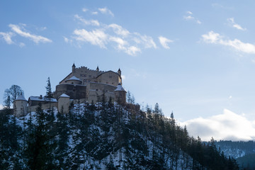 The Hohenwerfen Castle perched on top of a small rocky hill in the Austrian Alps on a beautiful and sunny winter day