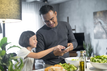 Happy Asian father spending time with daughter in the kitchen.