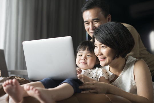 Happy Asian family looking at the computer together at home.