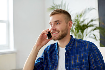 smiling young man calling on smartphone at office