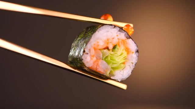 Sushi roll in chopsticks over black background. Seafood. Healthy eating, dieting concept. 4K UHD video footage. 3840X2160