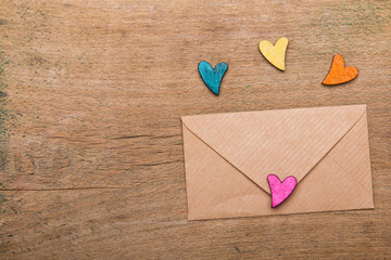 Small colorful hearts and envelope on wooden background. Copy space. Valentine's day background.