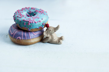 a small elephant figurine propped up with two different colored donuts, free space for text.