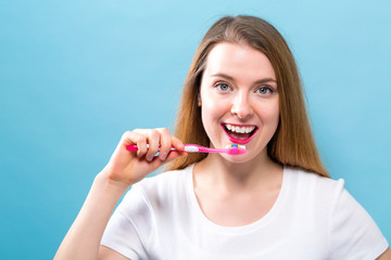 Young woman holding a toothbrush on a solid background