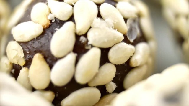 Heap of chocolate balls candies in sugar glaze isolated on white green background. Candy peanuts with sesame seeds similar to easter eggs