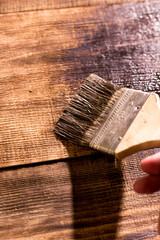 male hand paint wooden surface with brown paint using a paintbrush