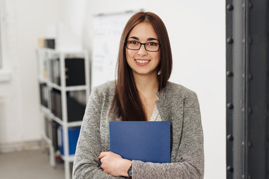Young smiling woman holding files in office