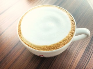 A white cup of hot coffee put on wooden table.