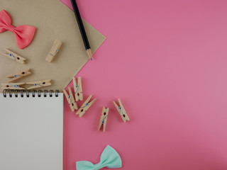 Flat lay,top view notebook.paper,pencil and wooden clips on pink background school desk,office supplied   with copy space Craft,education concept