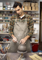 Young man making pottery in workshop