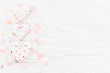 pink cookie hearts on white rustic wooden background with confetti in soft light. happy mother's day greeting card. space for text . happy valentine's day or women's. mock-up