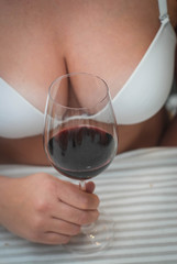 A Glass of Red Wine Holding by A Blurred girl in White Bra. Wine and Drink Concept.
