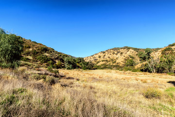 Hiking into dry California hillside on sunny morning