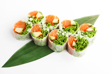 bright spring rolls with salmon and avocado on a bamboo leaf on a white background
