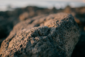 Volcanic stone on the rocky shore of the ocean on the sunset