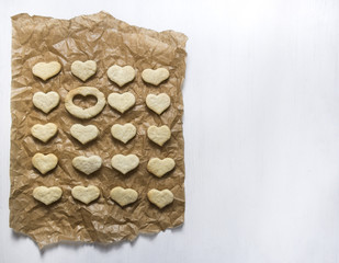 on a white background on baking paper lies a cookie in the shape of a heart and one place is empty 