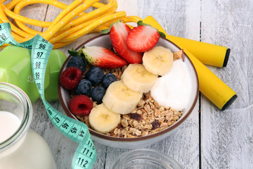 muesli with dairy and fruit, healthy lifestyle. bowl of cereal, fruit and dumbbell