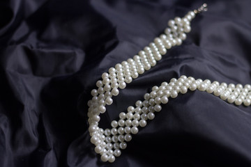 Women's necklace made of white pearls isolated on black background close up 