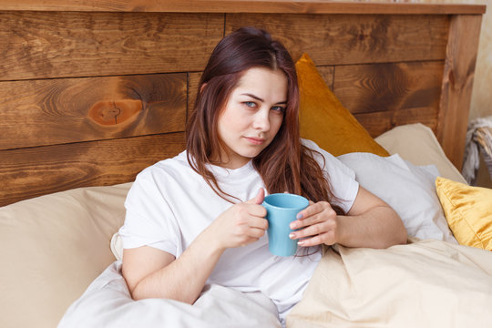 Half Asleep Young Woman Drinking Coffee On Bed.