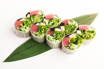 bright spring rolls with tuna, black caviar and greens on a bamboo leaf on a white background