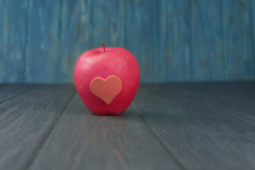 ripe red apple with heart on a wooden background on holiday in february valentine's day