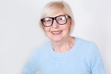 Portrait of a smiling old woman wearing glasses. Beautiful modern grandmother is 70 years old - a pensioner.