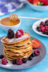 Fluffy and delicate pancakes with powdered sugar, honey, milk and berries.