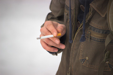 A male hand holds an inflamed cigarette