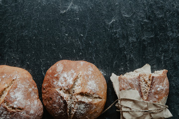 Healthy bread freshly from oven with packing paper on dark stone