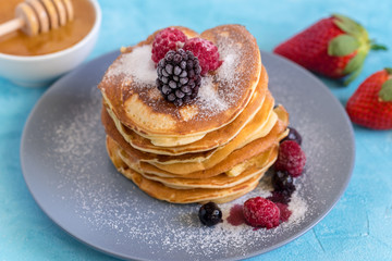 Fluffy and delicate pancakes with powdered sugar and berries.