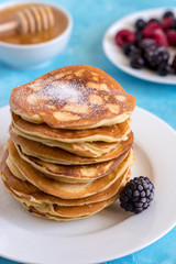 Fluffy and delicate pancakes with powdered sugar and berries.