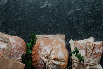 Homemade loaf of bread with packing paper and boxwood on the bottom of stone background