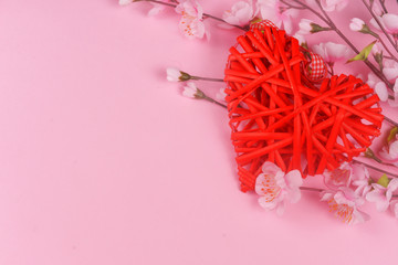 beautiful wicker red heart with pink flowers on a pink background on holiday february valentine's day