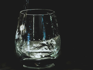 water pours into the glass isolated on the table water splash