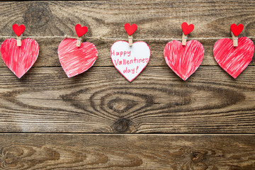 Multicolored hearts with inscriptions on a rope on a wooden background