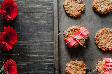 Gluten free biscuits with red paper and flowers on the side of black, vintage table