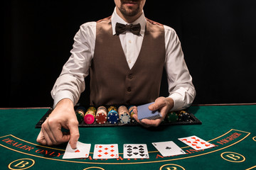 Close up of holdem dealer with playing cards and chips on green table
