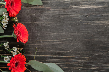 Red and white flowers with eucalyptus on the side of vintage, black table