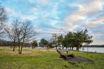 Beautiful morning landscape. Bench on the shore of the lake.