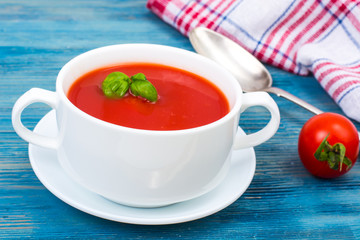 Cream soup of fresh red tomatoes on blue wooden background