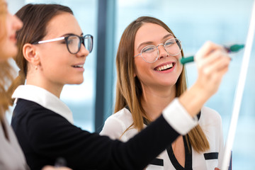 girl with glasses draws a marker on a whiteboard