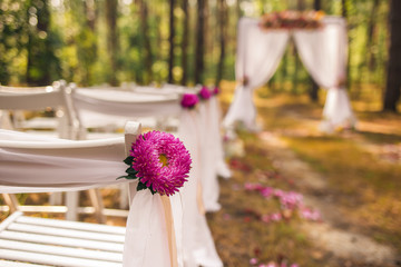 Closeup view of beautiful floral elements of wedding decorations. Settings for romantic wedding ceremony outside at sunny forest. Horizontal color photography. 