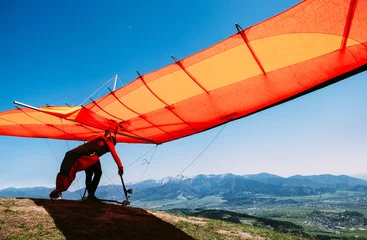 Fototapete Sport Mann mit Drachenflieger beginnt von der Bergkuppe zu fliegen